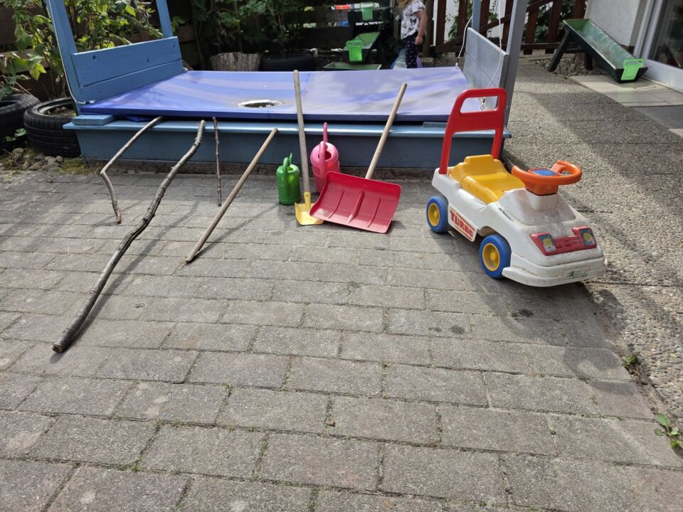 Spielmaterial und Bobbycar im Garten der Regenbogen-Kinder
