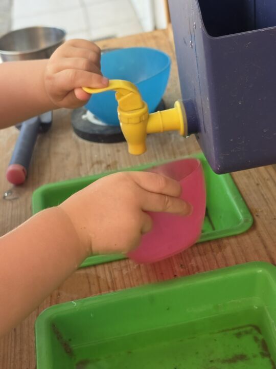 Kinderhände beim Schöpfen und Umfüllen von Wasser